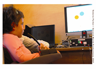 This Photo shows a 5 year old girl with paraplegia using the Voice Control  System with her computer program to move colored balls into a box using her voice.